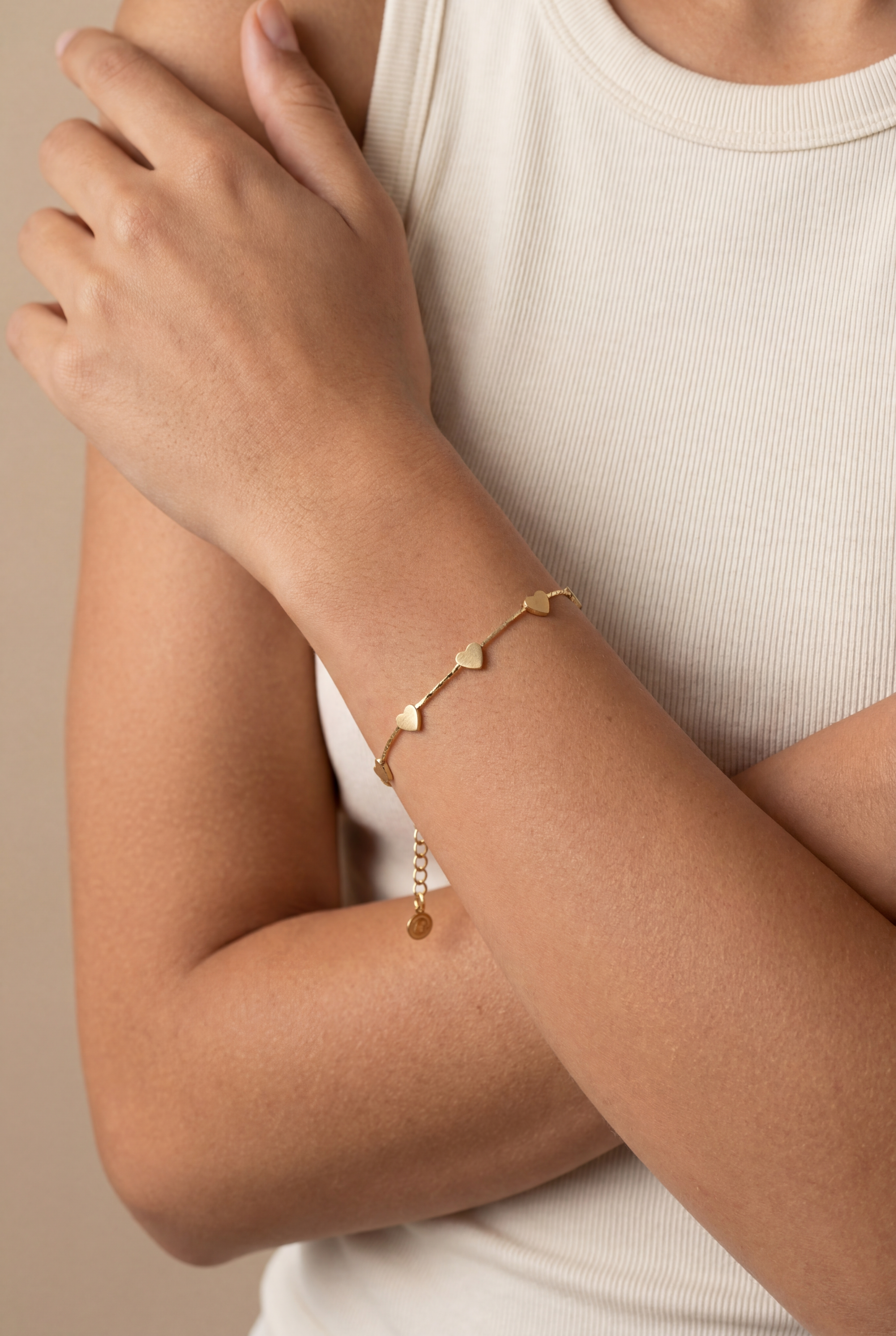 Gold bracelet on a person's wrist with a neutral background